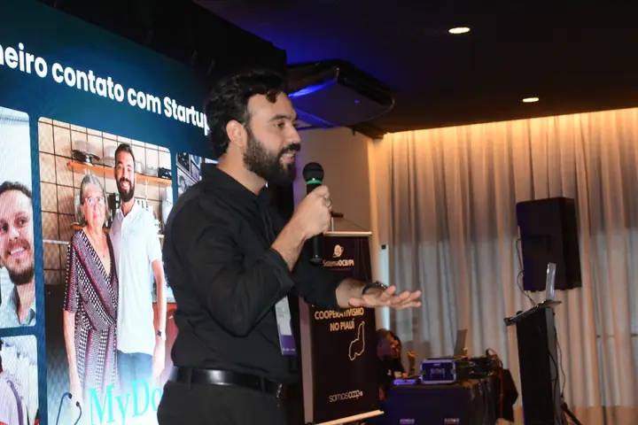 Gabriel Esteves apresentando em frente a um telão